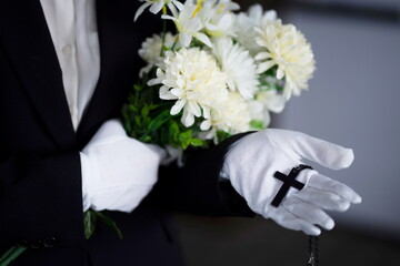 Bereaved holding flowers with cross at funeral