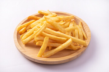 French fries placed on a round wooden plate, white background, selective focus.