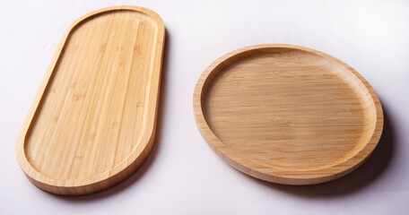 Two empty wooden dishes one round the other long, white background, selective focus.