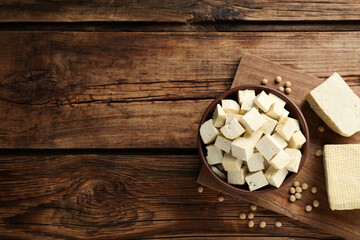 Cut tofu and soya beans on wooden table, flat lay. Space for text