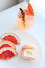 Cold lemonade of fresh grapefruit juice, alcohol and ice cubes decorated slice citrus and twig rosemary 