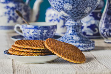 Close-up traditional Dutch sweet and crispy stroopwafels over blue Dutch tableware.