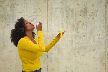 African american woman with afro hair and yellow t-shirt blowing soap bubbles.