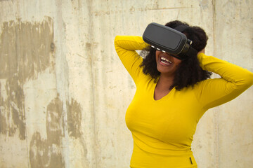 African american woman with afro hair and yellow t-shirt playing with virtual goggles.