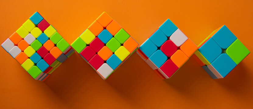 Araras, S&atilde;o Paulo, Brazil, April 4, 2021, Four magic cubes with different difficulties on orange background and shadow, top view.