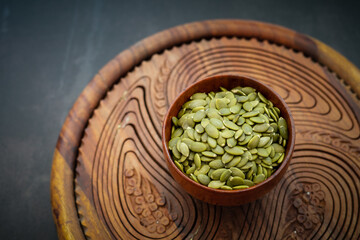 Top view of sunflower seeds in a wooden bowl on a wooden dark background.