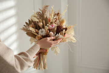 Woman holding beautiful dried flower bouquet at home, closeup - Powered by Adobe