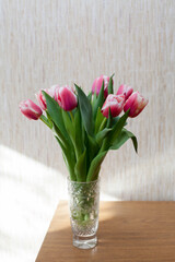 Few pink tulips in   crystal vase on   table
