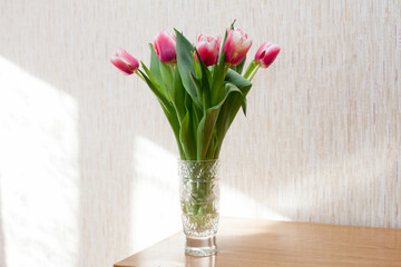 Few pink tulips in   crystal vase on   table