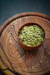 Top view of sunflower seeds in a wooden bowl on a wooden dark background.