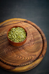 Top view of sunflower seeds in a wooden bowl on a wooden dark background.