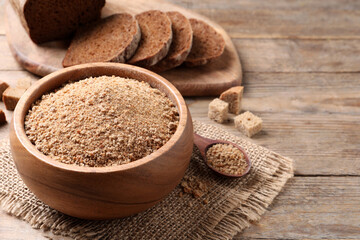 Fresh breadcrumbs in bowl on wooden table. Space for text