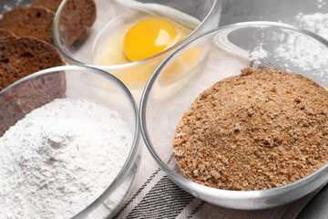 Fresh breadcrumbs, flour and egg on table, closeup