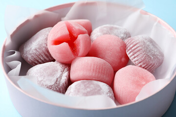 Many different delicious mochi in box on light blue background, closeup. Traditional Japanese dessert