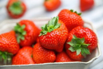 Closeup of isolated ripe fresh strawberries from german farmers market in cardboard box on white wood table