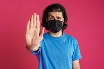 White man in face mask frowning and showing stop gesture at camera