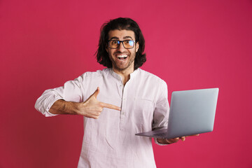 Unshaven excited man holding and pointing finger at laptop