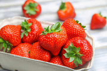 Closeup of isolated ripe fresh strawberries from german farmers market in cardboard box on white wood table