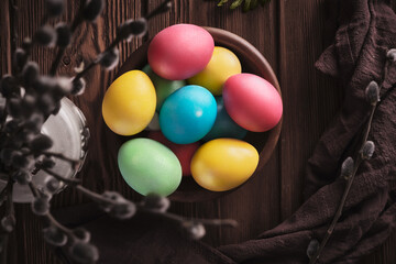 Multicolored painted eggs for easter with pussy willow sprig on wooden background