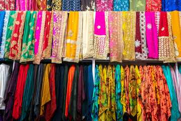 Rolls of fabric and textiles for sale stacked on shelves in shop,View of cloth rolls of different colors and patterns on shelves in fabric store, Colorful traditional indian, turkey costumes