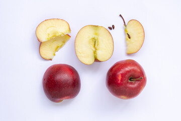 A red apple, two halves, slices and two seeds are isolated on a light background. Top view.