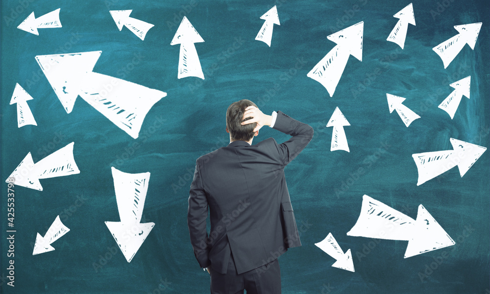 Poster Making decision in business concept with man in black suit looking at blackboard with lots of arrows directed in different directions