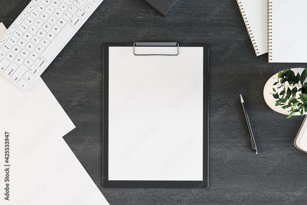 Poster blank white paper list in black tablet on black office table with white keyboard and green plant in 