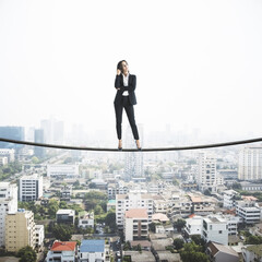 Fototapeta na wymiar Professional strategy concept with businesswoman standing confidently on a tightrope above city
