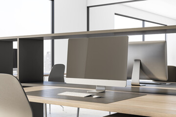 Blank modern computer monitor on wooden table in stylish coworking office. 3D rendering, mock up