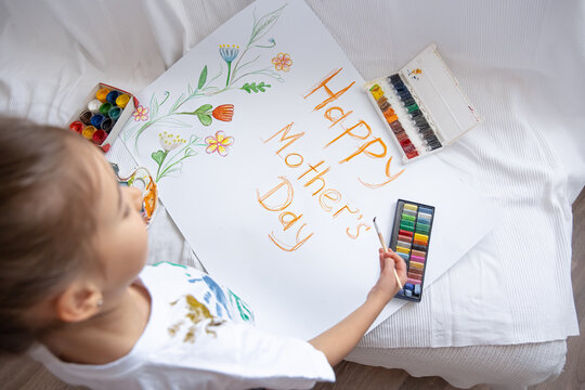 Little girl drawing mothers day holiday card top view.