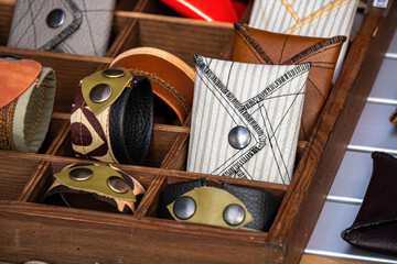 Handmade wallets and bracelets, made of leather and fabric, with metal rivets, on a store shelf. Fashion accessory