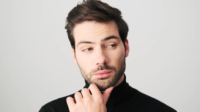 A close-up view of a thinking man is posing to the camera standing over white background