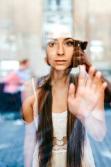 Portrait of young beautiful romantic brunette girl with long hair posing behind glass