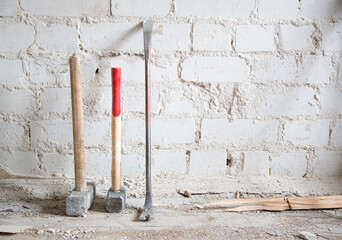 Dusty construction tools near white brick wall