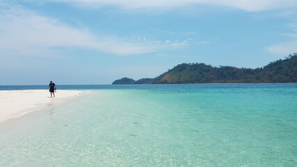 A man walking on a white sand beach