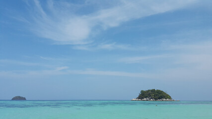 Beautiful white clouds on blue sky over calm sea with sunlight reflection.Sunny sky and calm blue ocean. Vibrant sea with clouds on horizon.