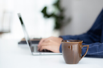 Hand of business man working from home using laptop computer to internet online on desk, lifestyle of new normal, social distancing, freelance work in stay home, employee using notebook indoor.