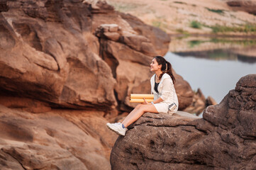 Young asian woman traveler with paper map on rock cliff in grand canyon