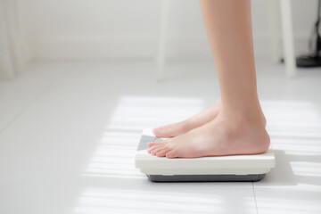 Lifestyle with leg of woman stand measuring weight scale for diet with barefoot, closeup foot of girl slim weight loss measure for food control and nutrition, healthy care and wellness concept.