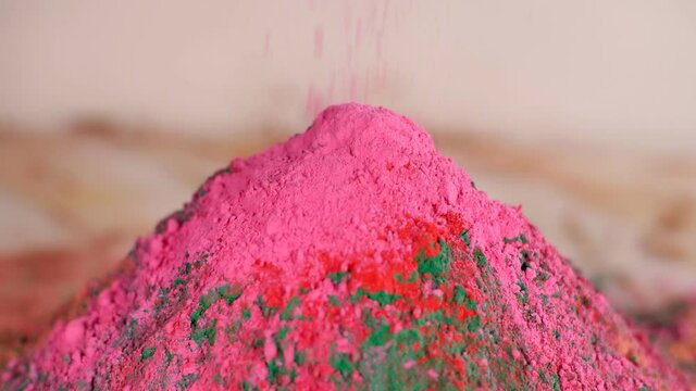 Bright pink color Gulal dropping on a heap of organic powder dry Holi colors. Holi festival celebration concept - Multicolor mixed Abeer / Abir placed beautifully for the popular occasion