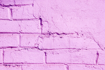Texture of a brick wall partially covered with plasterwork and painted in pink color