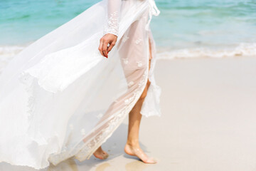 beautiful girl in a white dress walks along the beach