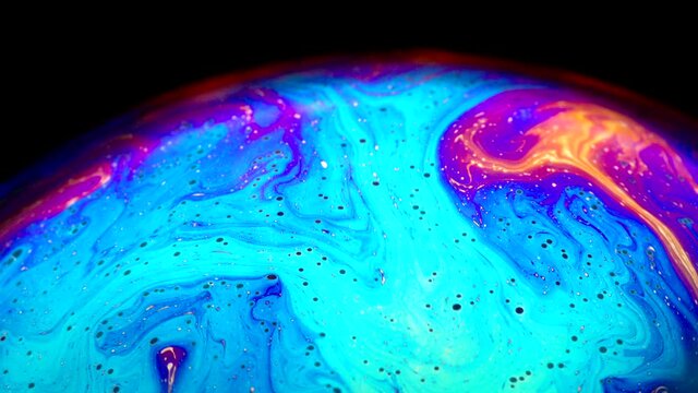 Fluid soap bubble looking like planets. Psychedelic colorful abstract art with urreal patterns of color in motion.