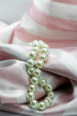 pearl necklace on soft pink satin white striped fabric