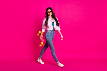 Full size profile photo of optimistic brunette nice lady go hold skate wear jacket jeans sneakers isolated on pink color background
