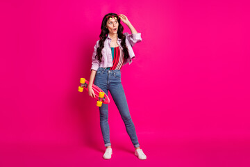 Full length photo of impressed woman wear jacket glasses holding skate board looking empty space...