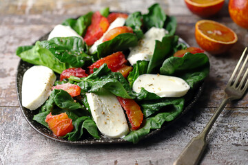 A la caprese salad with spinach, mozzarella and orange. Healthy food. Diet concept. Beautiful and delicious salads.
