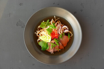 Asian soup Ramen with pork and noodles iserved on gray background