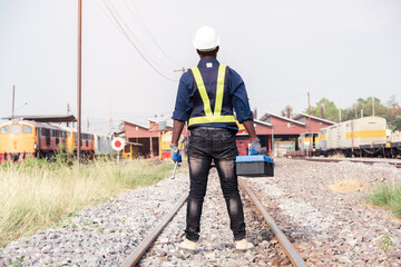 Fototapeta premium African machine engineer technician wearing a helmet, groves and safety vest is using a wrench to repair the train