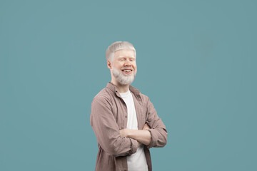 Successful albino man posing with crossed arms, wearing casual clothes and smiling to camera over turquoise background